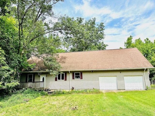 rear view of house featuring a garage and a lawn