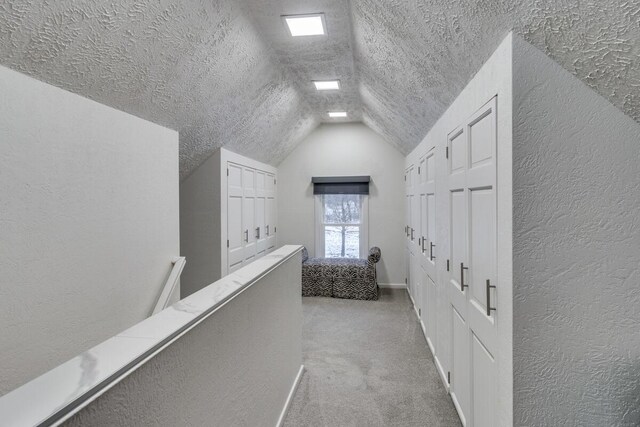 corridor with light carpet, a textured ceiling, and vaulted ceiling