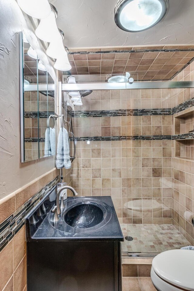 bathroom featuring vanity, tile walls, tile patterned flooring, toilet, and a shower with shower door