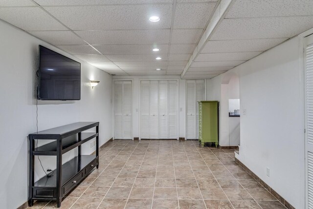 basement with light tile patterned floors and a paneled ceiling