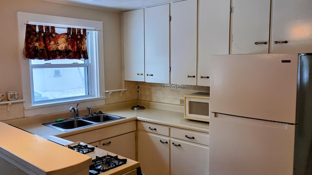 kitchen with backsplash, sink, white cabinets, and white appliances