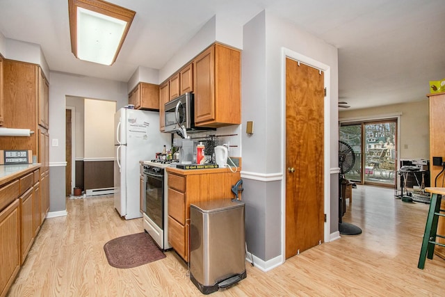 kitchen featuring a baseboard radiator, light hardwood / wood-style flooring, gas range oven, white refrigerator, and decorative backsplash