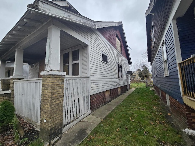 view of side of home with a yard and covered porch