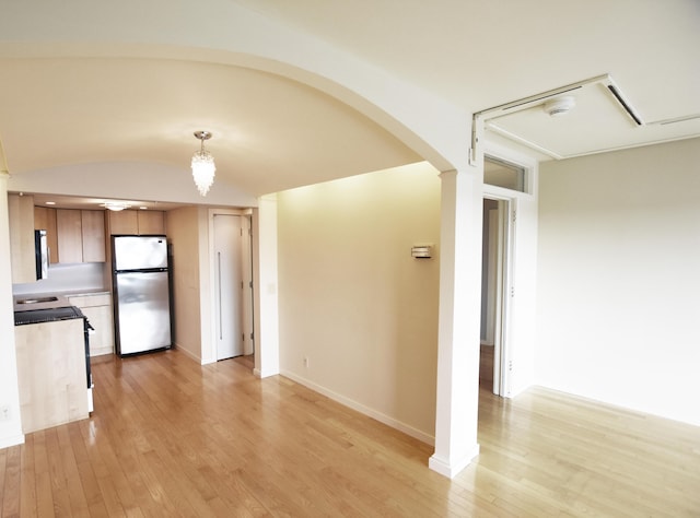 kitchen featuring light hardwood / wood-style floors, decorative light fixtures, and stainless steel fridge