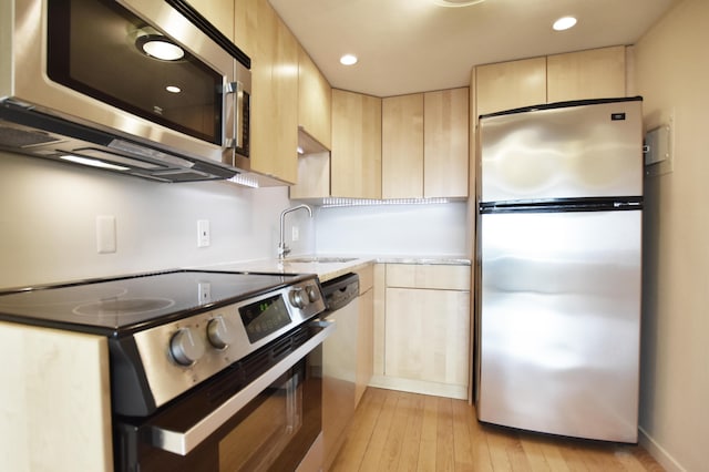 kitchen with light brown cabinetry, appliances with stainless steel finishes, sink, and light hardwood / wood-style flooring