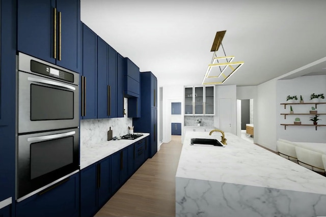 kitchen with blue cabinetry, sink, tasteful backsplash, pendant lighting, and double wall oven