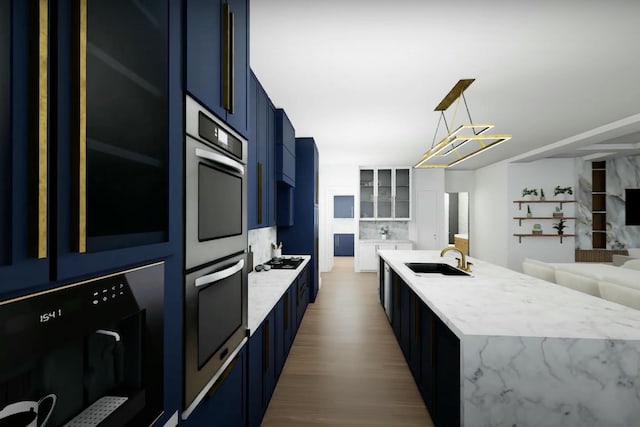 kitchen featuring pendant lighting, a center island with sink, sink, hardwood / wood-style flooring, and blue cabinetry