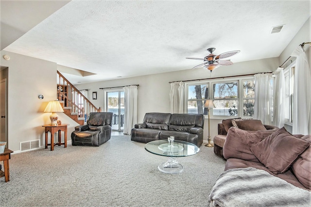 carpeted living room featuring ceiling fan and a textured ceiling