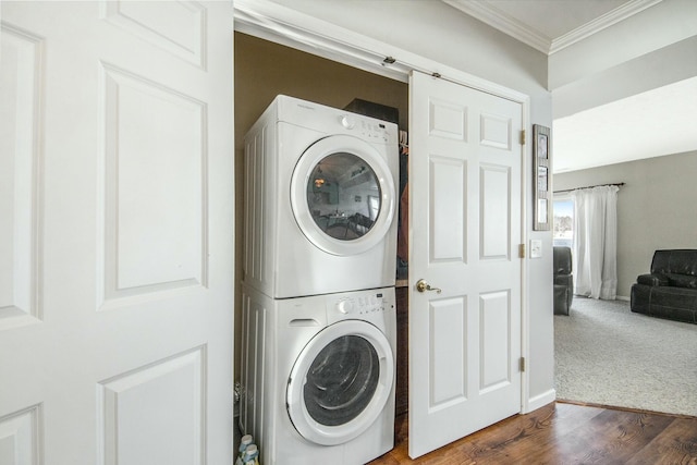 laundry room with stacked washer and dryer, crown molding, and dark carpet