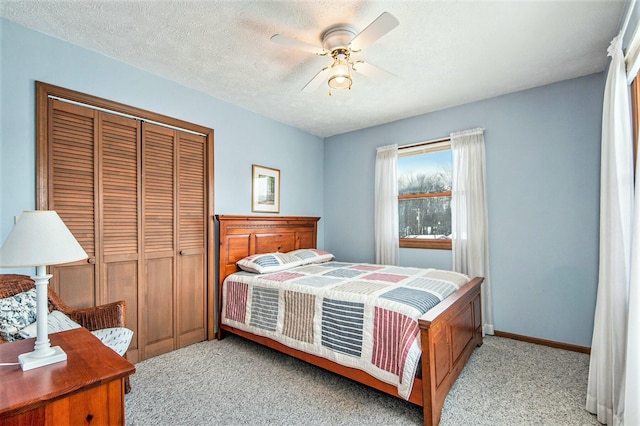 carpeted bedroom with ceiling fan, a closet, and a textured ceiling