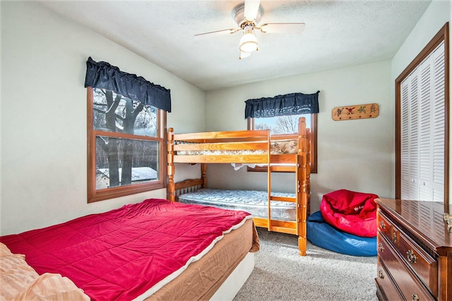 carpeted bedroom with a textured ceiling, a closet, and ceiling fan