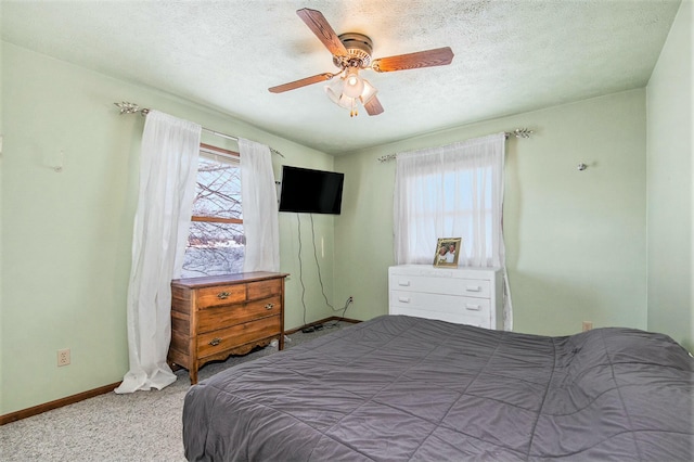 bedroom with ceiling fan, carpet floors, and a textured ceiling