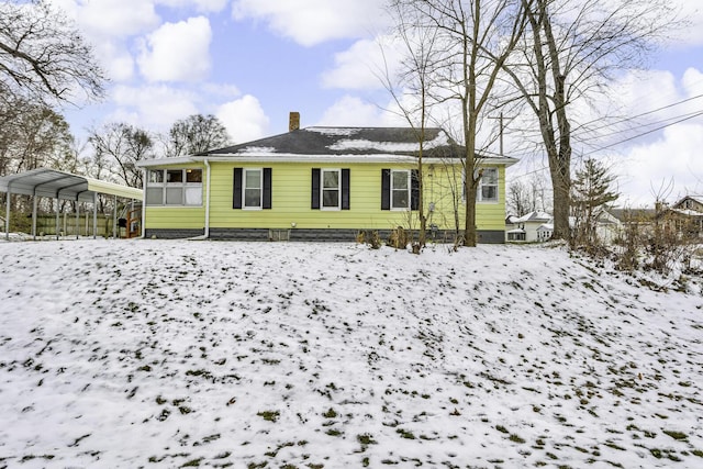 snow covered property with a carport and a sunroom