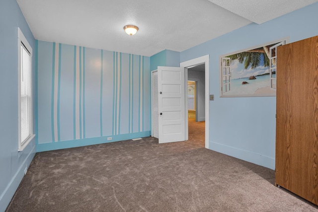 unfurnished bedroom with dark colored carpet and multiple windows