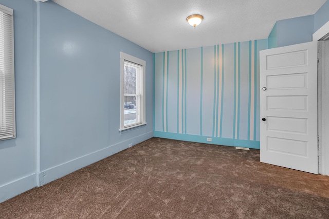 empty room with dark colored carpet and a textured ceiling