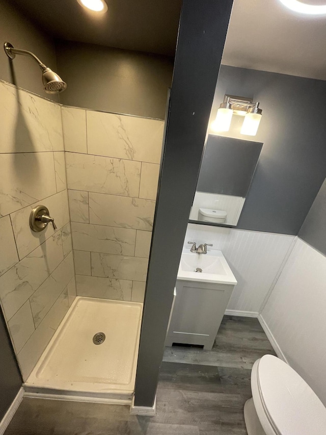 bathroom featuring a tile shower, vanity, hardwood / wood-style flooring, and toilet