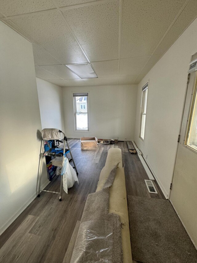 interior space featuring a paneled ceiling and dark hardwood / wood-style flooring