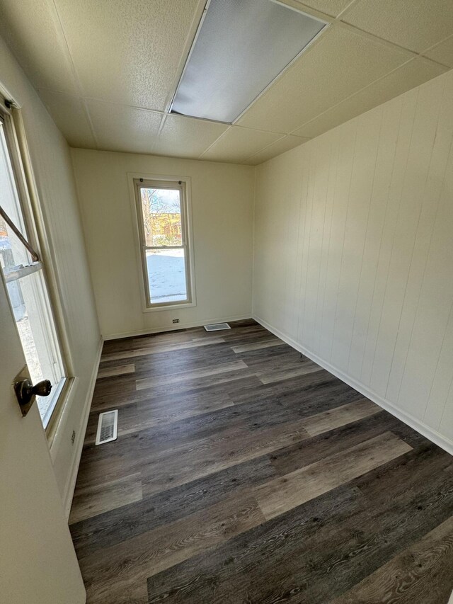 empty room featuring a drop ceiling and dark hardwood / wood-style floors