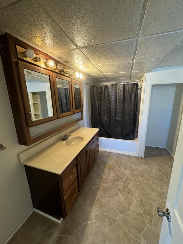 bathroom featuring a drop ceiling, shower / bath combination with curtain, and vanity