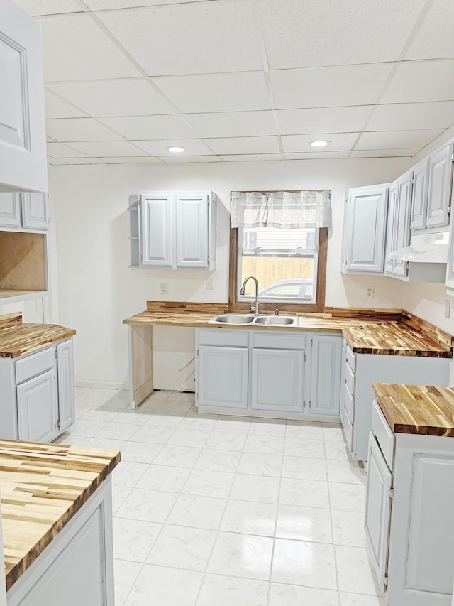 kitchen featuring a drop ceiling, butcher block counters, and sink