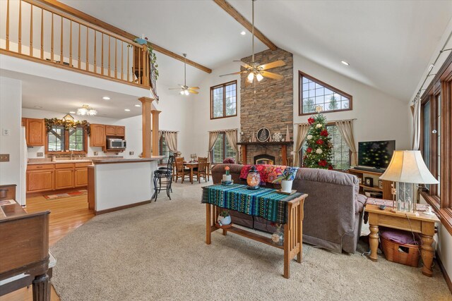 living room featuring a fireplace, high vaulted ceiling, a healthy amount of sunlight, and light hardwood / wood-style floors