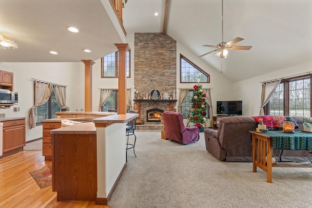 living room featuring plenty of natural light, ceiling fan, light wood-type flooring, and a fireplace