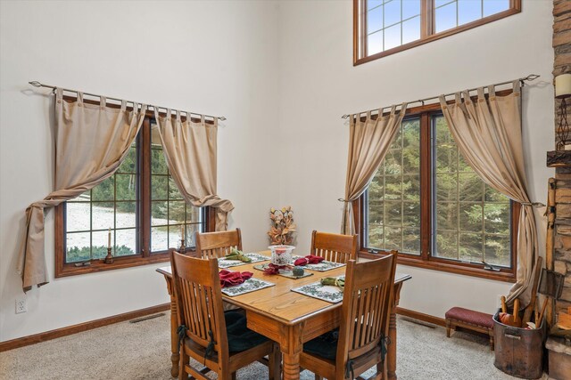 dining room with carpet, a towering ceiling, and a wealth of natural light