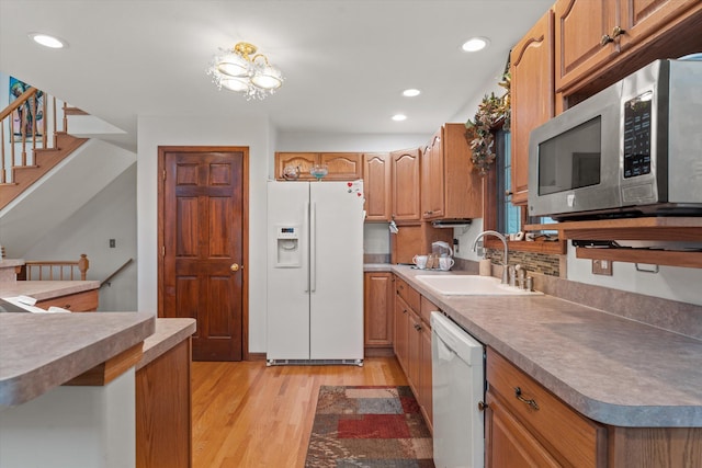 kitchen featuring a notable chandelier, light wood-type flooring, white appliances, and sink