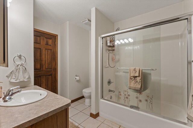 full bathroom featuring toilet, vanity, tile patterned floors, and enclosed tub / shower combo