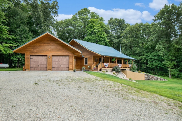 log home with covered porch, a front yard, and a garage