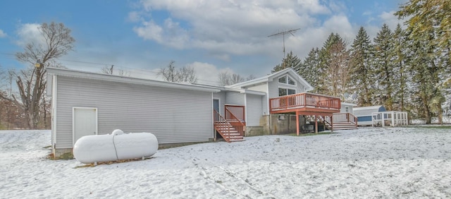 snow covered back of property with a wooden deck