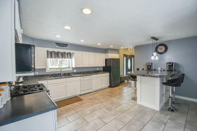 kitchen with pendant lighting, dishwasher, a breakfast bar, black fridge, and white cabinetry