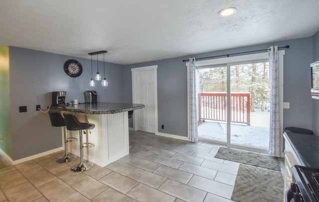 kitchen featuring kitchen peninsula, a kitchen breakfast bar, stainless steel range, hanging light fixtures, and light tile patterned flooring