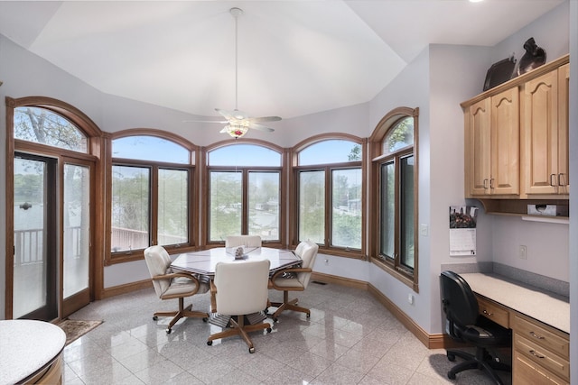 dining room featuring ceiling fan, plenty of natural light, built in desk, and lofted ceiling