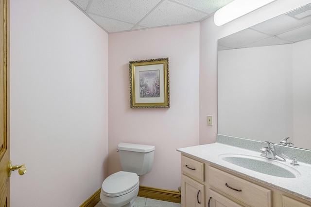 bathroom with tile patterned flooring, vanity, toilet, and a drop ceiling