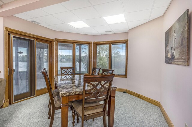 carpeted dining space with a paneled ceiling