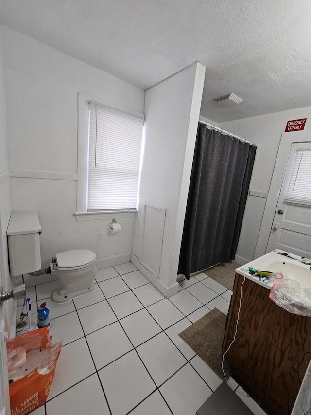 bathroom featuring tile patterned flooring, vanity, a textured ceiling, and toilet