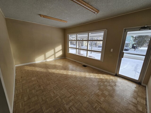 empty room featuring a textured ceiling and parquet flooring