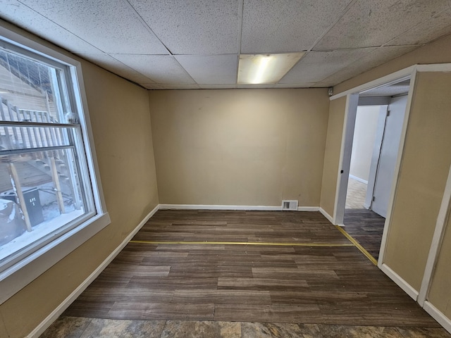 empty room featuring a paneled ceiling and dark hardwood / wood-style floors