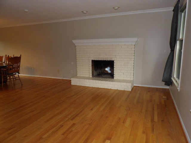 unfurnished living room featuring wood-type flooring, a brick fireplace, and ornamental molding