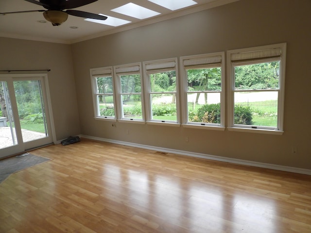 unfurnished room with light wood-type flooring, a skylight, plenty of natural light, and ceiling fan