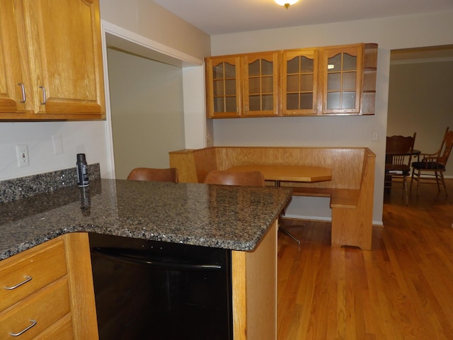 kitchen with kitchen peninsula, black dishwasher, light hardwood / wood-style floors, and dark stone countertops