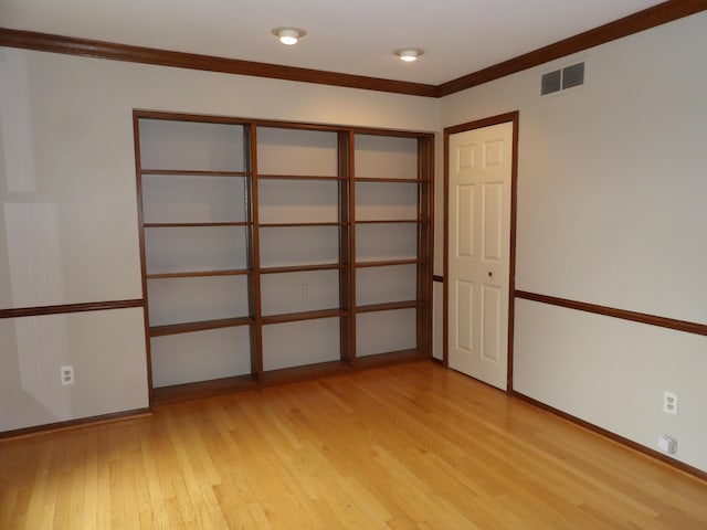 empty room featuring light wood-type flooring and ornamental molding