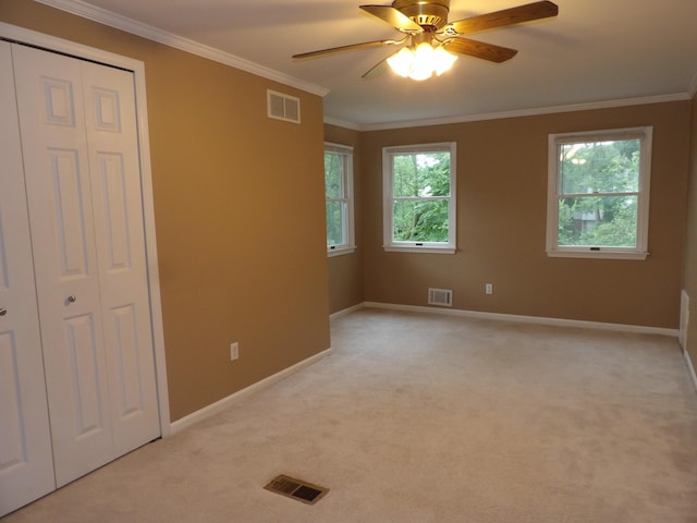 unfurnished bedroom featuring light carpet, a closet, ceiling fan, and ornamental molding