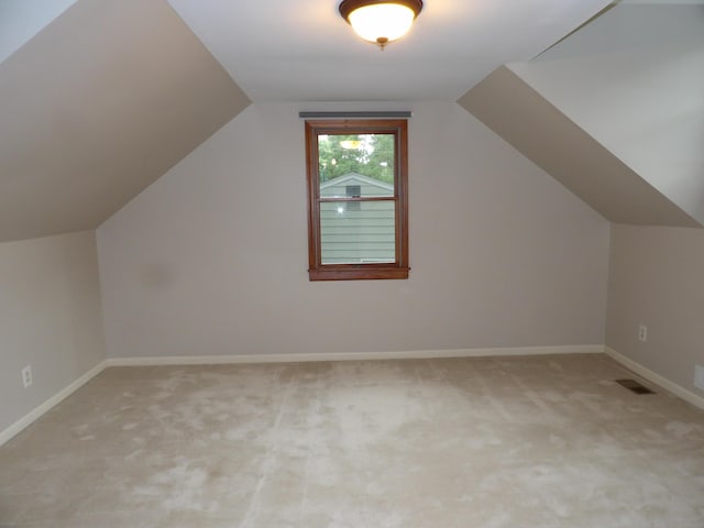 additional living space featuring light colored carpet and lofted ceiling