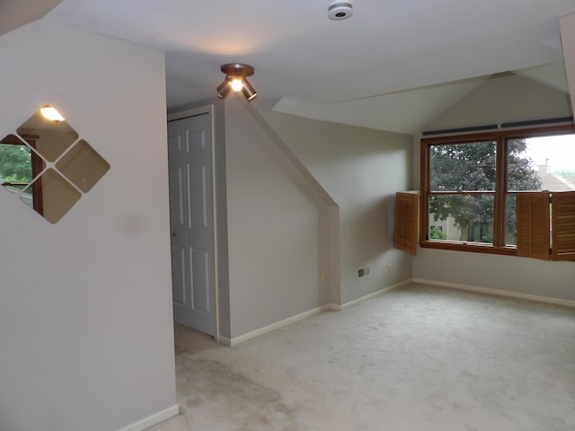 additional living space featuring light colored carpet and vaulted ceiling