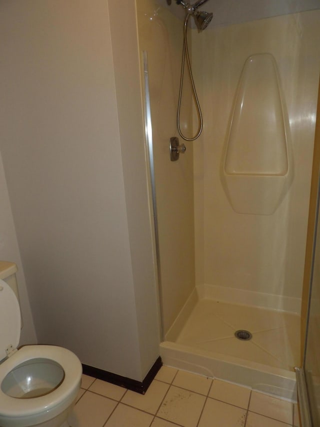 bathroom with tile patterned floors, toilet, and a shower