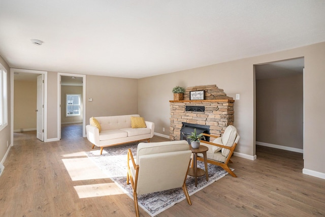 living room featuring a stone fireplace and light wood-type flooring