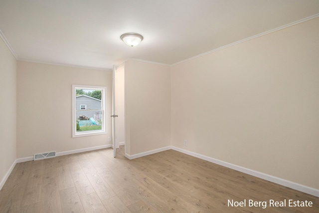 spare room with ornamental molding and light wood-type flooring