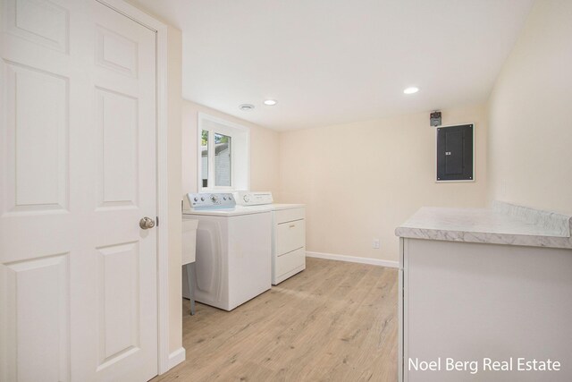 laundry area featuring washer and dryer, electric panel, and light hardwood / wood-style floors